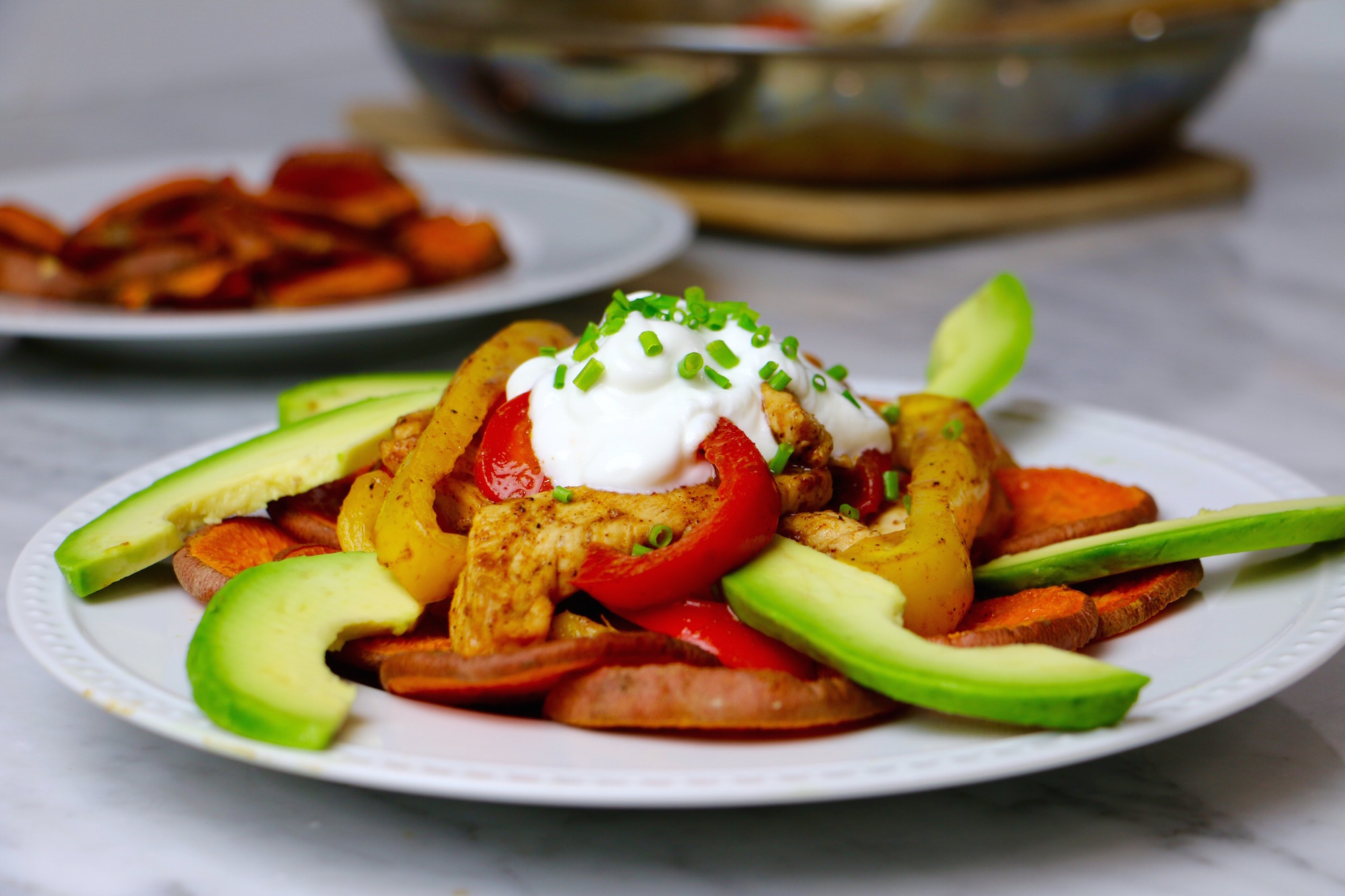 Healthy Chicken Fajita Nachos made with Baked Sweet Potato Chips and topped with organic chicken, red and yellow bell peppers, avocado, and greek yogurt. Gluten-free + can be made vegan by swapping beans. Takes 30 minutes to make!